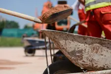 Workers digging, shoveling earth into a wheelbarrow 